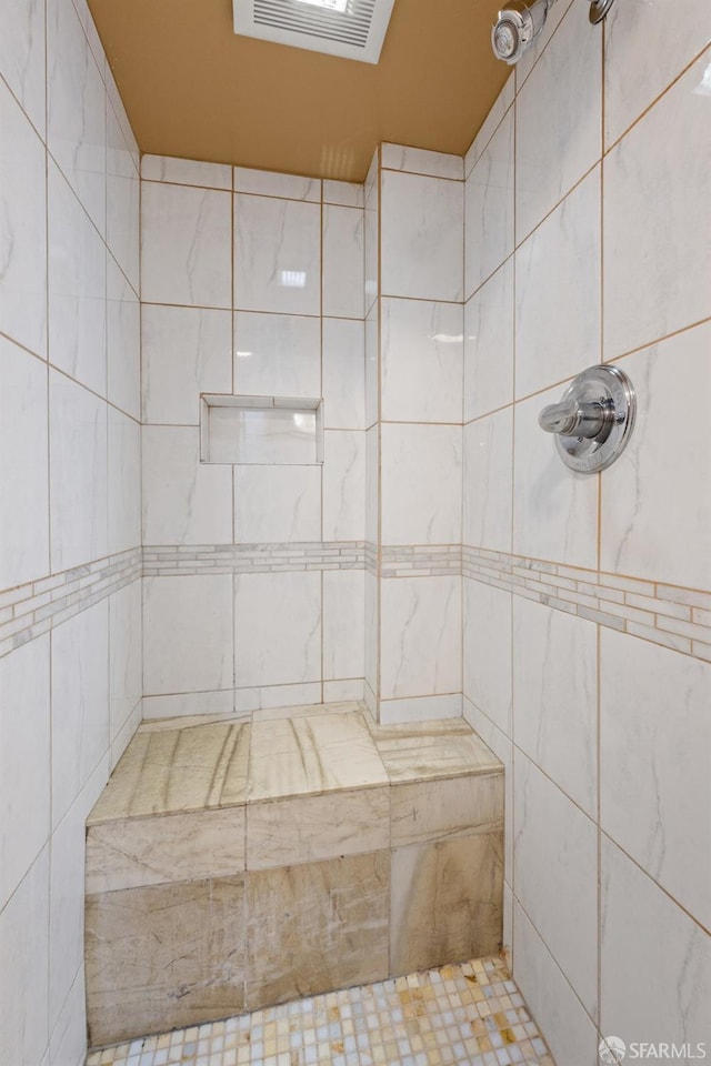 bathroom featuring a tile shower and visible vents