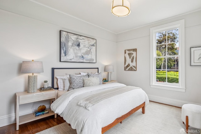 bedroom featuring baseboards, wood finished floors, and multiple windows