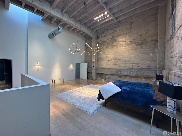 bedroom featuring hardwood / wood-style flooring, a towering ceiling, and a notable chandelier