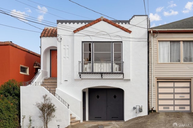 mediterranean / spanish home featuring a balcony, a tile roof, and stucco siding