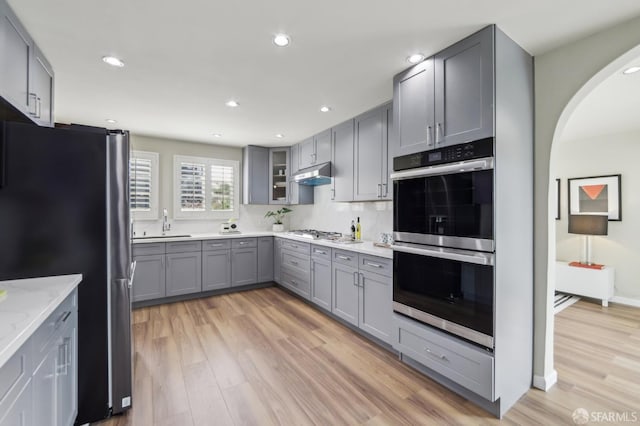 1475 Monterey Blvd, San Francisco, CA 94127 - kitchen featuring appliances with stainless steel finishes, gray cabinetry, light wood-type flooring, under cabinet range hood, and arched walkways