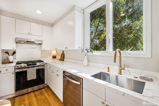 kitchen featuring extractor fan, appliances with stainless steel finishes, sink, white cabinets, and light stone counters