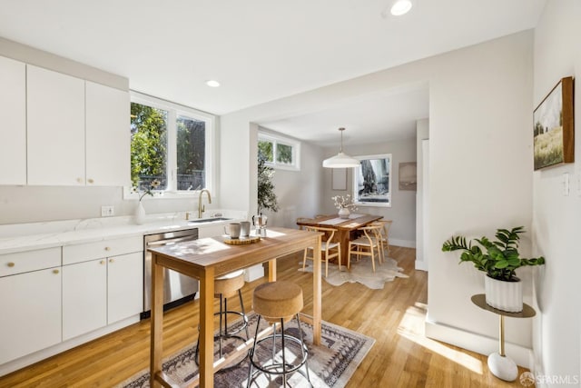 kitchen featuring white cabinetry, dishwasher, sink, and pendant lighting