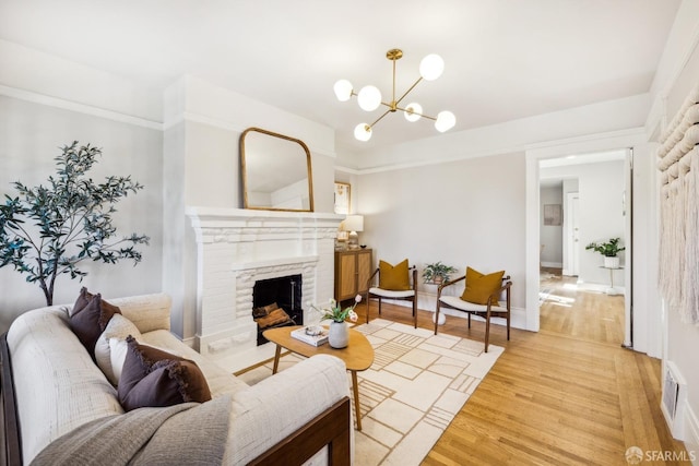 living room featuring a fireplace, a notable chandelier, and light hardwood / wood-style flooring