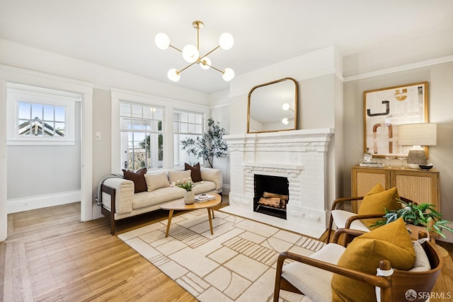 living room with a brick fireplace, a notable chandelier, and light hardwood / wood-style flooring