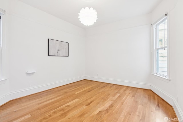 spare room featuring hardwood / wood-style flooring and an inviting chandelier