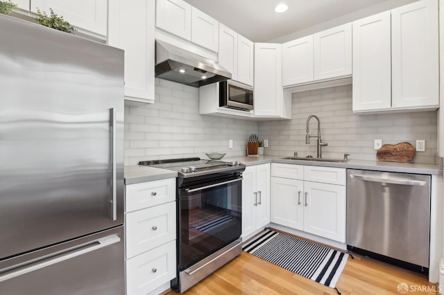 kitchen featuring sink, white cabinets, wall chimney range hood, and appliances with stainless steel finishes