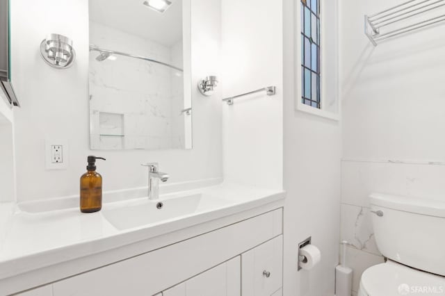 bathroom featuring toilet, walk in shower, and vanity