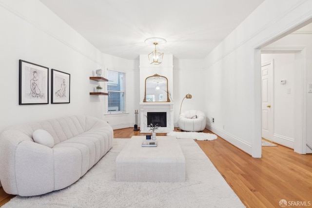 living room featuring hardwood / wood-style flooring, a large fireplace, and a chandelier