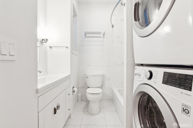 full bathroom with tile walls, shower / tub combination, toilet, stacked washer / drying machine, and vanity