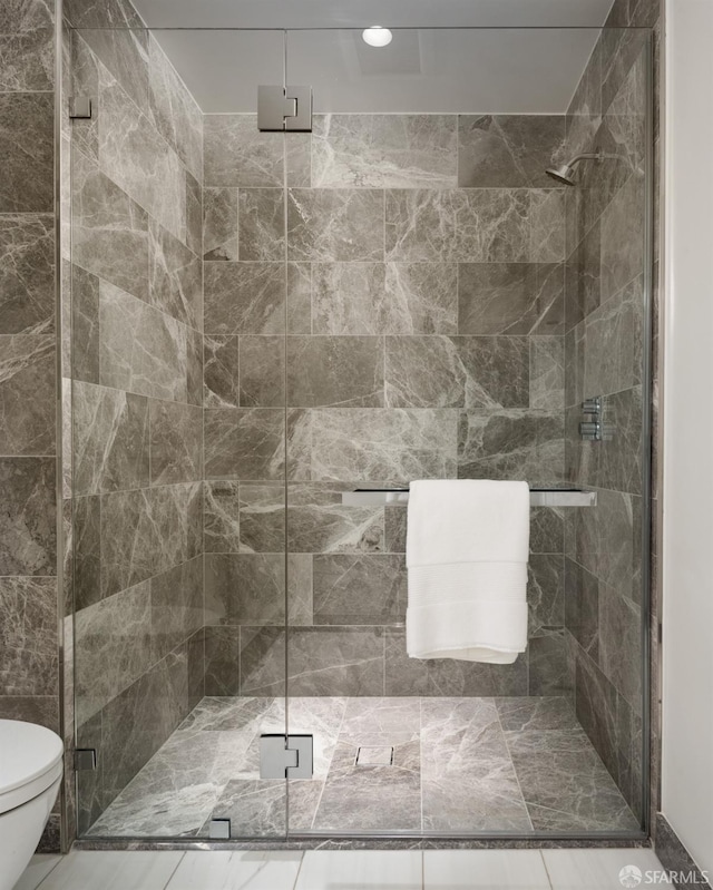 bathroom featuring a shower with shower door and toilet