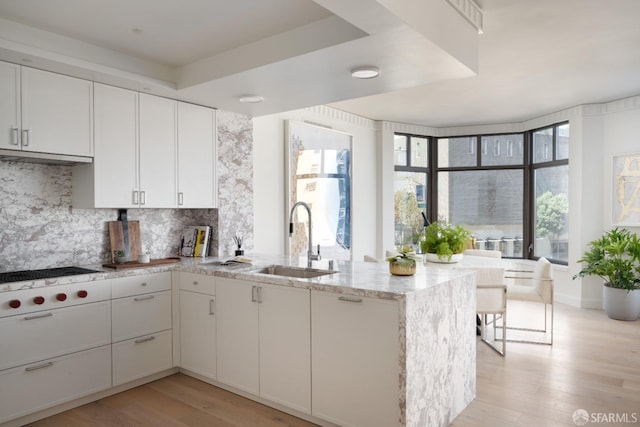 kitchen with white cabinets, light wood-type flooring, and sink