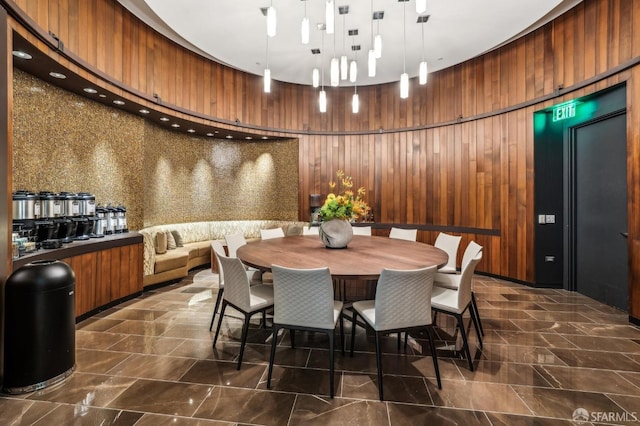 dining room featuring wood walls and a towering ceiling