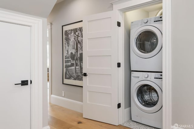 clothes washing area featuring stacked washing maching and dryer and light wood-type flooring