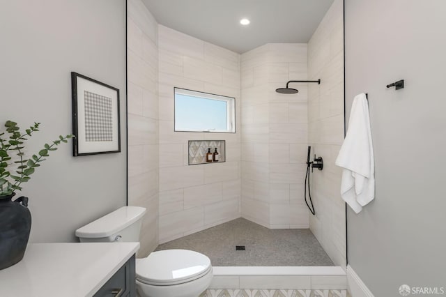 bathroom with vanity, tile patterned flooring, toilet, and tiled shower