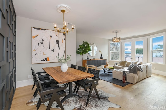 dining area featuring french doors, a chandelier, and light hardwood / wood-style floors