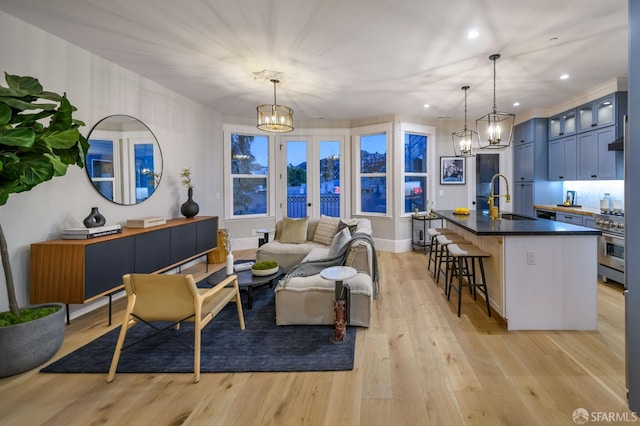 living room with sink, a notable chandelier, and light hardwood / wood-style flooring