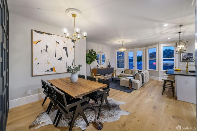 dining area with light wood-type flooring and a notable chandelier