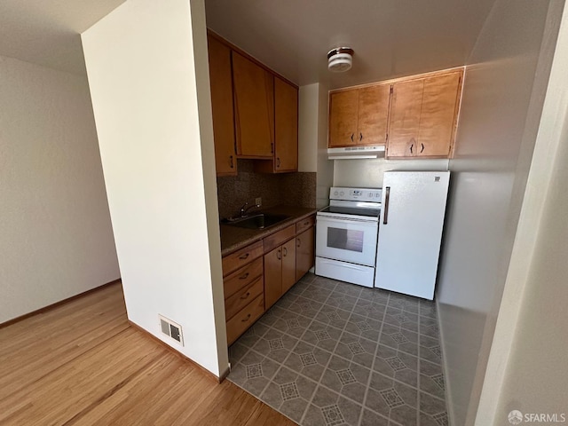 kitchen with white appliances, hardwood / wood-style floors, decorative backsplash, and sink