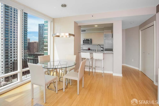 dining space with floor to ceiling windows, sink, and light hardwood / wood-style flooring