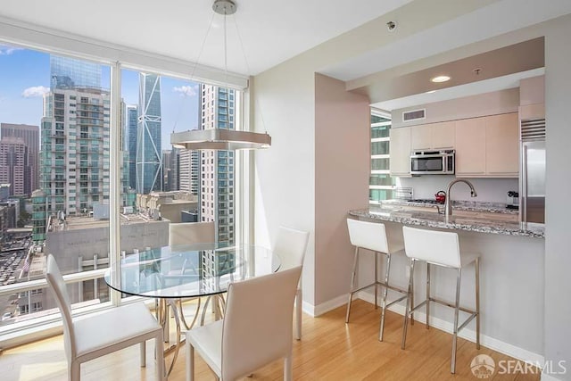 interior space with light stone counters, white cabinetry, light wood-type flooring, a wall of windows, and stainless steel appliances