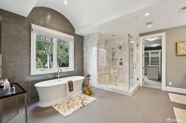 bathroom featuring tile patterned flooring, lofted ceiling, shower with separate bathtub, and tile walls