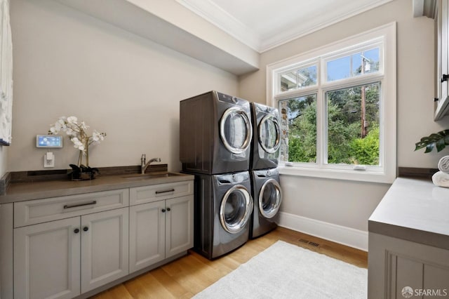 laundry room featuring stacked washer / drying machine, cabinets, plenty of natural light, and sink