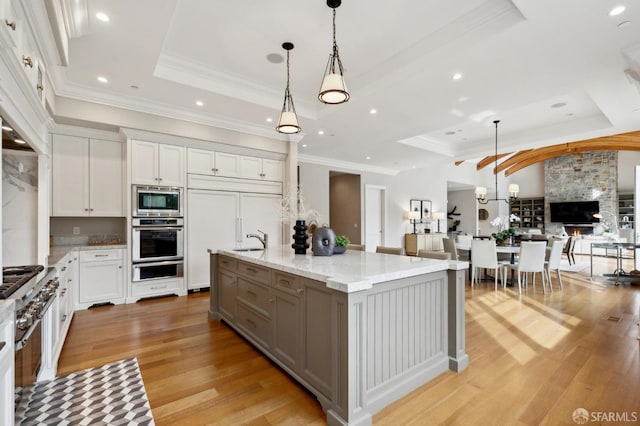 kitchen with white cabinetry, a raised ceiling, a spacious island, pendant lighting, and appliances with stainless steel finishes