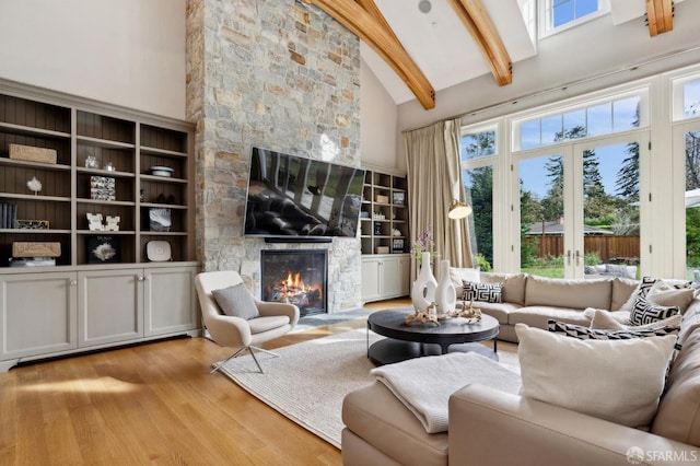 living room with french doors, light wood-type flooring, beam ceiling, high vaulted ceiling, and a fireplace