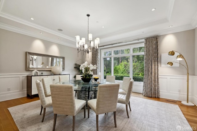 dining room with a raised ceiling, crown molding, a chandelier, and hardwood / wood-style flooring