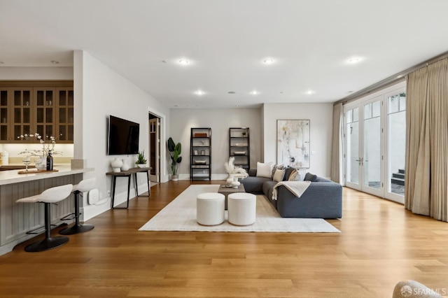 living room featuring french doors, indoor bar, and light hardwood / wood-style floors