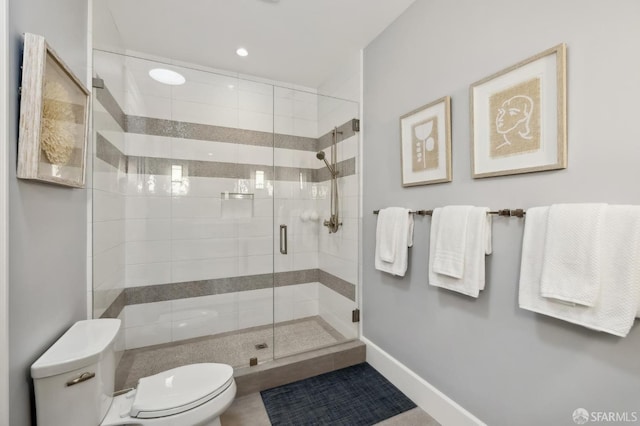 bathroom featuring a shower with shower door and toilet