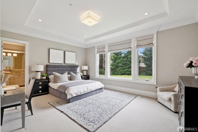 carpeted bedroom with a tray ceiling, ensuite bath, and ornamental molding