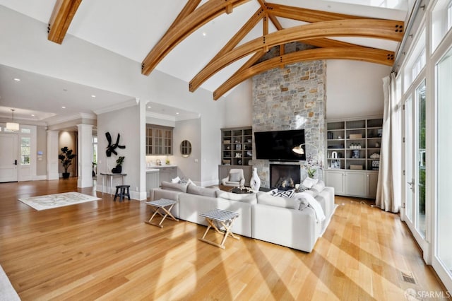 living room featuring a fireplace, high vaulted ceiling, a healthy amount of sunlight, and light hardwood / wood-style flooring