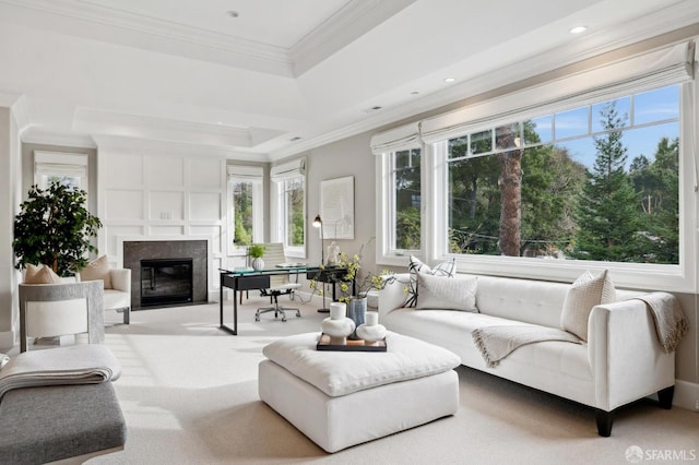 carpeted living room with a tray ceiling, crown molding, and a high end fireplace