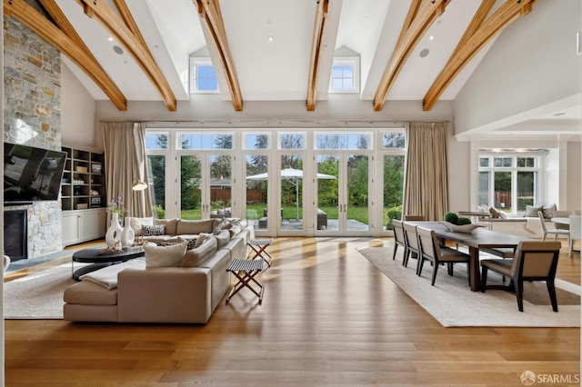 sunroom with vaulted ceiling with beams, a fireplace, and french doors