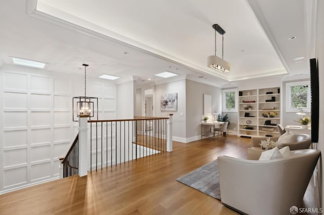 living room with built in shelves, ornamental molding, a chandelier, and hardwood / wood-style flooring