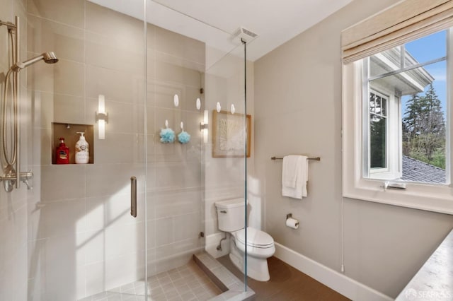 bathroom with hardwood / wood-style flooring, toilet, and a shower with door