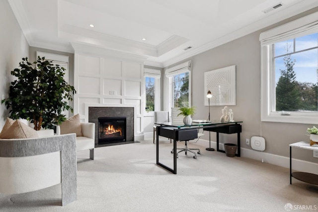 carpeted office space featuring a tray ceiling, a fireplace, and ornamental molding