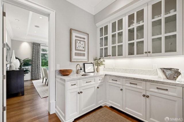 bar featuring light stone countertops, dark hardwood / wood-style flooring, crown molding, sink, and white cabinetry