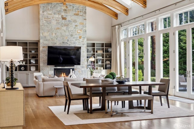 dining space featuring a fireplace, light wood-type flooring, high vaulted ceiling, and built in features