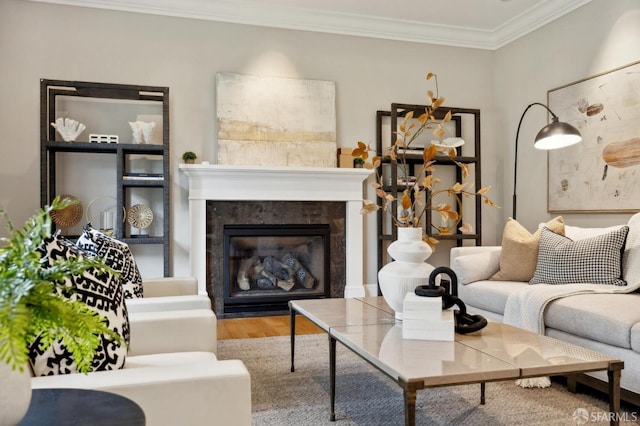 living room featuring a tiled fireplace, wood-type flooring, and ornamental molding