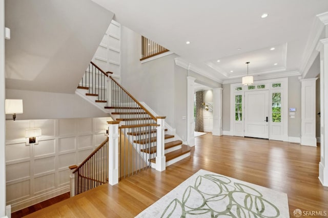 foyer featuring ornate columns, crown molding, and wood-type flooring