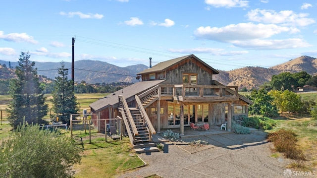 rear view of property with a rural view, a mountain view, and a patio