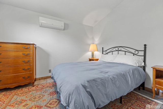 bedroom with lofted ceiling, an AC wall unit, and light hardwood / wood-style floors