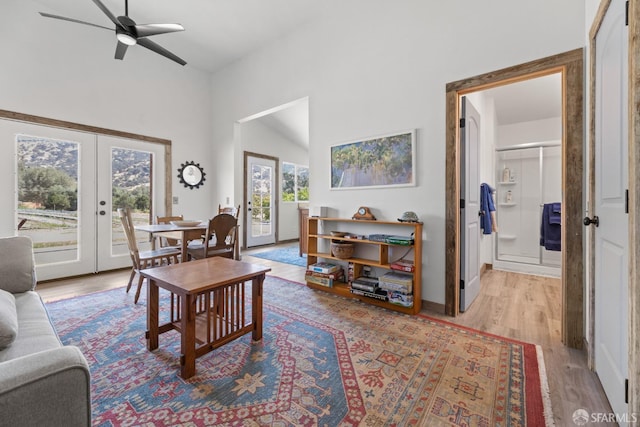 living area with high vaulted ceiling, french doors, a ceiling fan, and light wood-style floors