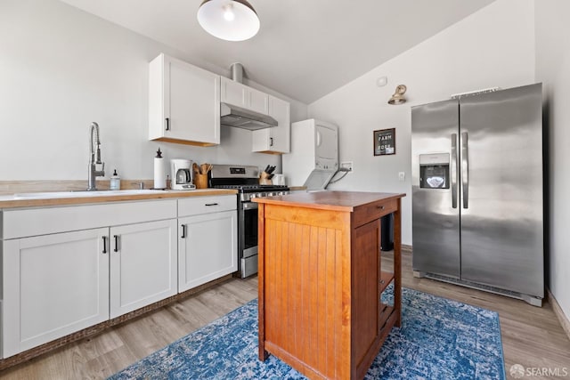 kitchen featuring stacked washer and dryer, appliances with stainless steel finishes, white cabinets, and light wood-type flooring