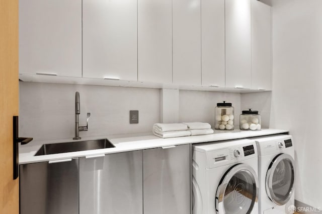 washroom featuring sink, cabinets, and washing machine and clothes dryer