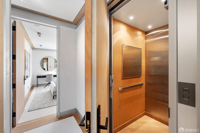 corridor featuring elevator and light hardwood / wood-style floors