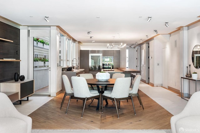 dining area featuring light hardwood / wood-style floors, a chandelier, sink, and a wealth of natural light